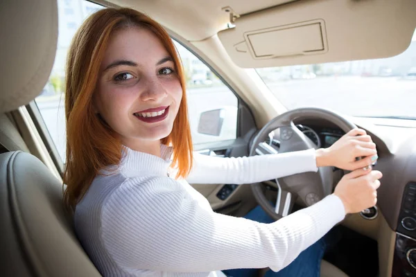 Молодая рыжая женщина-водитель за рулем автомобиля улыбается — стоковое фото