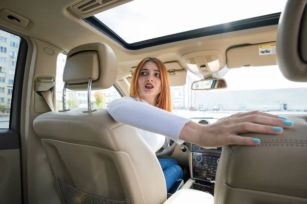 Amplia vista angular de una joven pelirroja conduciendo un coche de vuelta — Foto de Stock