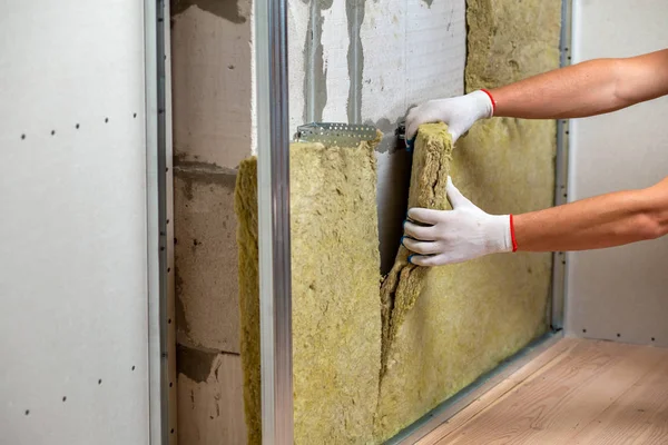 Robotnik izolujący ścianę pomieszczenia wełną mineralną termiczną — Zdjęcie stockowe