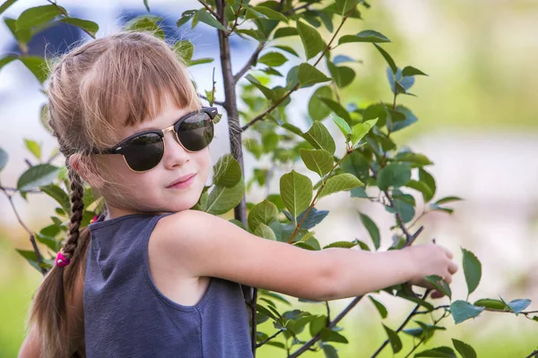 Jovem menina bonita em óculos de sol na moda abraçando verde — Fotografia de Stock