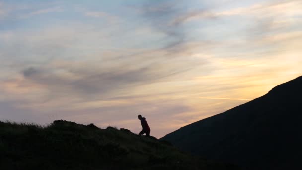 Gün Batımında Dağa Tırmanan Bir Yürüyüşçünün Karanlık Silueti Ellerini Kaldırarak — Stok video