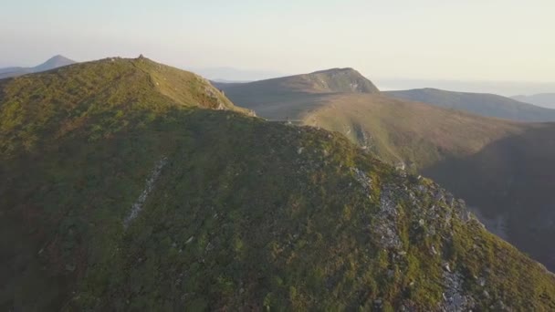 岩の多い山の上に立つハイカーは壮大な景色を楽しんでいます 山の中で日の出を見る登山家 — ストック動画