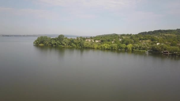 Vue aérienne d'un petit village en zone rurale entre des arbres verts sur le rivage d'un grand lac .