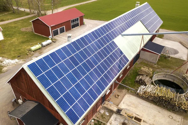 Draufsicht auf eine blaue Photovoltaik-Solaranlage auf einem Holzgebäude, einer Scheune oder einem Hausdach. Erneuerbare ökologische Ökoenergie-Produktionskonzept. Stockbild