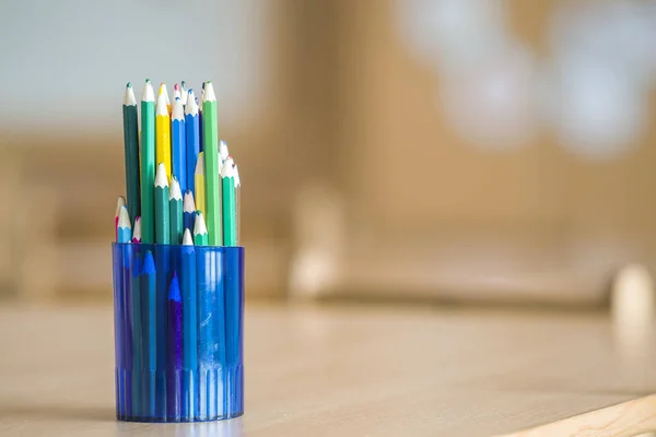 Wooden colorful drawing pencils arranged in plastic jug on light — Stock Image Wooden colorful drawing pencils arranged in plastic jug on light Stock Photo