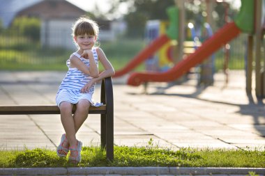 Kısa elbiseli sevimli genç kız playgro açık havada yalnız oturuyor