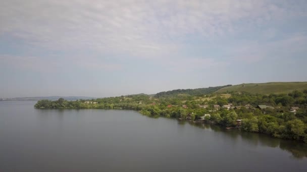 Vue aérienne d'un petit village en zone rurale entre des arbres verts sur le rivage d'un grand lac .