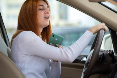 Direksiyonun başında cep telefonuyla konuşan mutlu kızıl kız. 