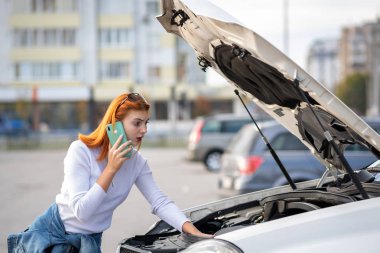 Kaputu patlamış, kırık bir arabanın yanında duran genç bir kadın konuşuyor.