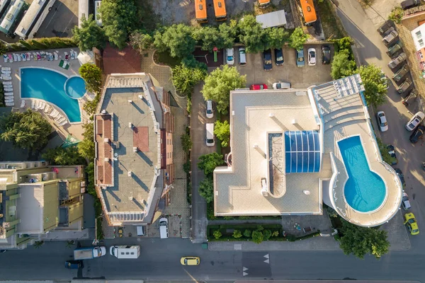 Top down aerial view of hotels roofs, streets with parked cars a