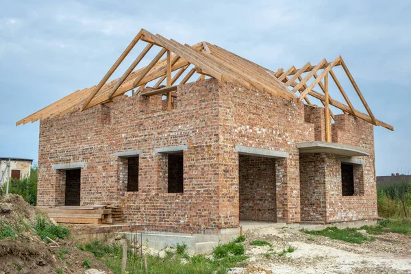 Building site with unfinished brick house with wooden roofing fr