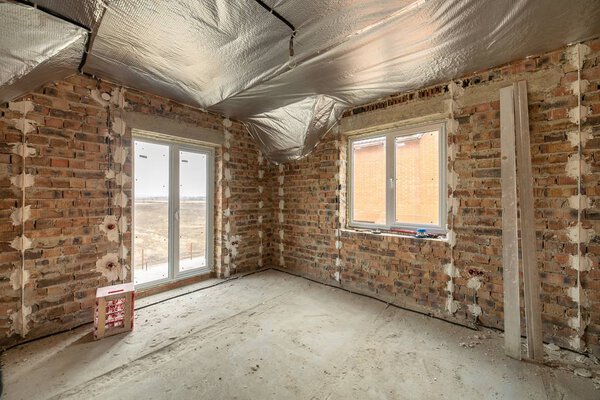 Интерьер незавершенного кирпичного дома с бетонным полом и голым
 