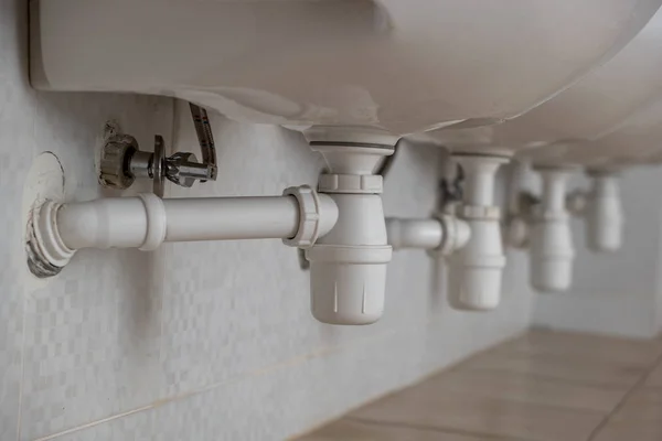 Primer plano del desagüe de tubo de plástico blanco bajo lavabo en bathr —  Fotos de Stock