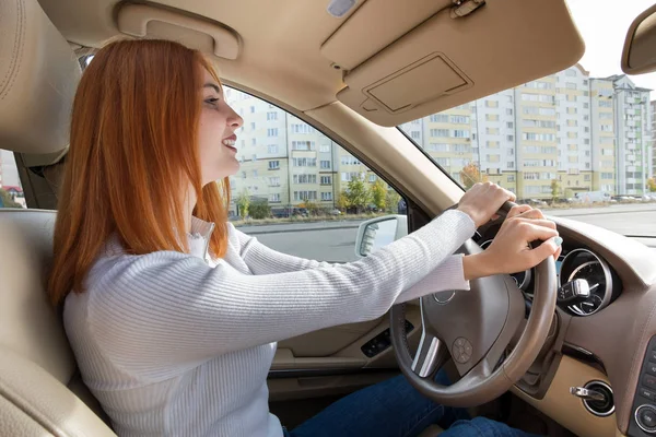 Молодая рыжая женщина-водитель за рулем автомобиля улыбается — стоковое фото