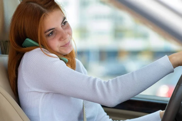 Szczęśliwa ruda dziewczyna rozmawia przez telefon komórkowy za kierownicą — Zdjęcie stockowe