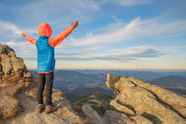 Niño pequeño excursionista de pie con las manos levantadas en las montañas en — Foto de Stock