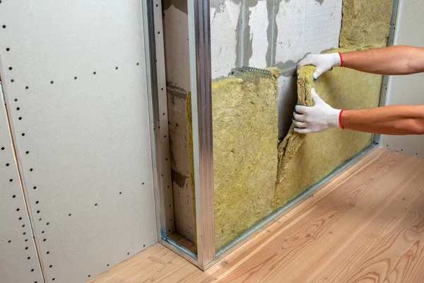Robotnik izolujący ścianę pomieszczenia wełną mineralną termiczną — Zdjęcie stockowe