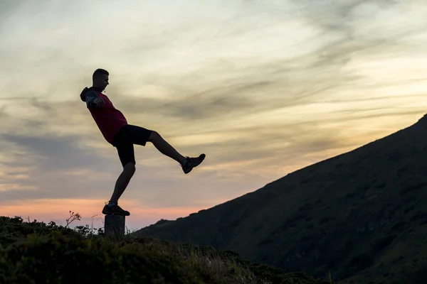 Silhueta escura de um caminhante que se equilibra em uma pedra de ápice à noite — Fotografia de Stock