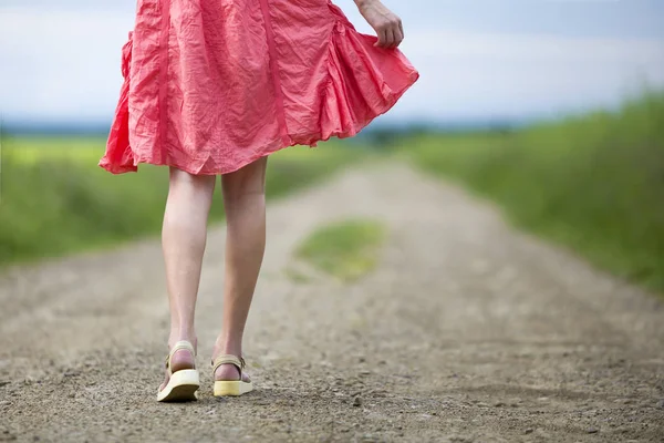 Vista posterior de la mujer joven en vestido rojo piernas caminando por tierra roa — Foto de Stock
