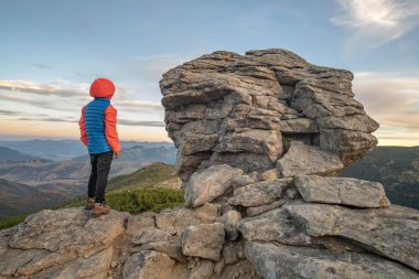 Genç çocuk yürüyüşçü dağlarda duruyor ama manzaranın tadını çıkarıyor.