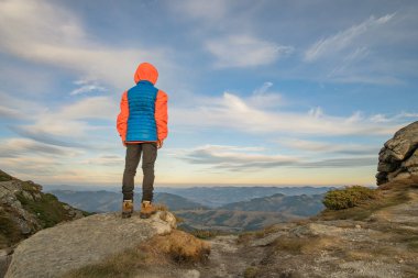 Genç çocuk yürüyüşçü dağlarda duruyor ama manzaranın tadını çıkarıyor.