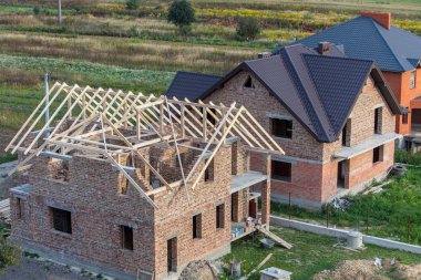 Yorumun altında ahşap çatı yapısı olan tamamlanmamış tuğla ev