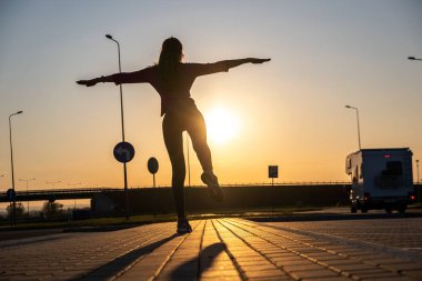 Genç bir kadının karanlık silueti boş bir otoparkta duruyor.