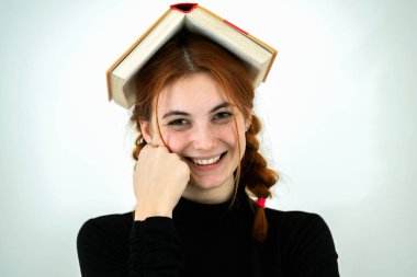 Elinde açık bir kitapla gülümseyen genç bir kızın portresi.