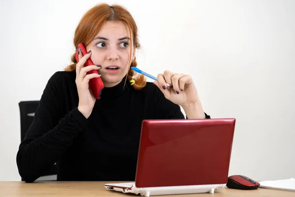 Ofiste çalışan genç bir kadın arkada cep telefonuyla konuşuyor. — Stok fotoğraf
