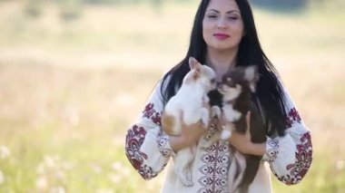 Kollarında iki küçük köpek tutan bir kadın..