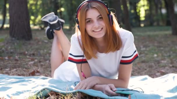 红头发的漂亮而积极的少女穿着粉色耳机听音乐 开心地笑着的画像 — 图库视频影像