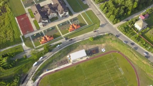 Letecký pohled na fotbalové hřiště na stadionu pokrytém zelenou trávou ve venkovské městské oblasti.