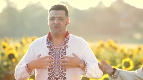 一群身穿乌克兰民族服装的快乐的年轻人在向日葵地里唱歌跳舞 — 图库视频影像
