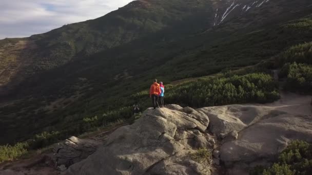 山の中の大きな岩の上に一緒に登るハイカーの男と彼の子供の空中ビュー — ストック動画