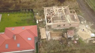 Biri ahşap çatı iskeleti ve diğeri de kırmızı kiremit çatılı iki özel evin yukarıdan aşağıya bakan görüntüsü..