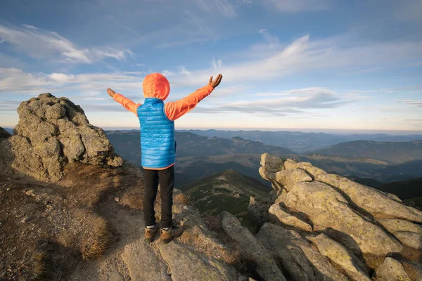 Jonge kind jongen wandelaar staan met opgeheven handen in de bergen en — Stockfoto