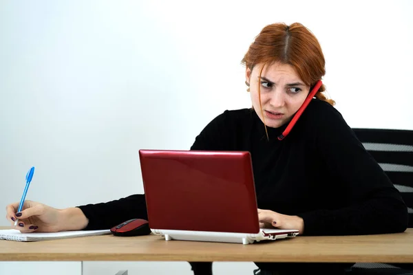 Mujer joven trabajadora de oficina hablando en un teléfono celular sentado detrás — Foto de Stock