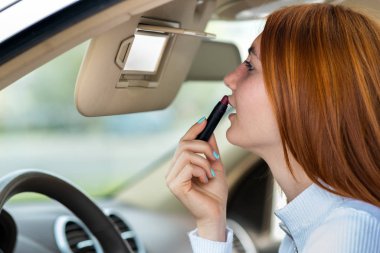 Kızıl saçlı genç bir kadının makyajını düzeltirken çekilmiş fotoğrafı.