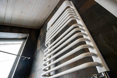 Siyah karoya monte edilmiş beyaz elektrikli havlu kurutma makinesi.