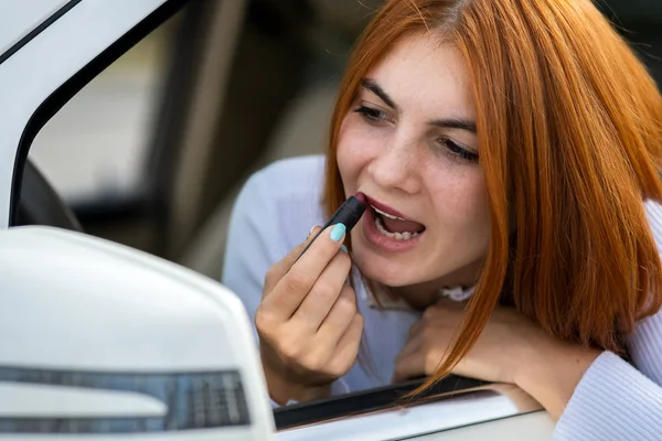 Detailní záběr mladé zrzky žena řidič opravuje její make-up wi — Stock fotografie
