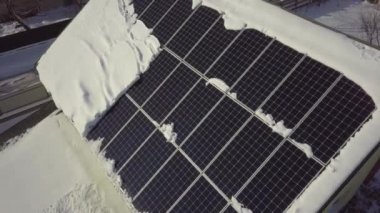 Closeup surface on a house roof covered with solar panels in winter with snow on top.