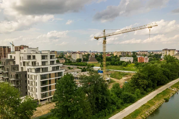 Aerial view of tower lifting crane and concrete frame of tall apartment residential building under construction in a city. Urban development and real estate growth concept.