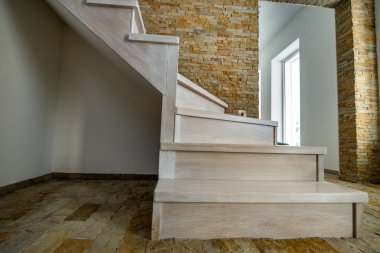 Çatı katının iç kısımlarında modern merdivenler var. Dekoratif kireçtaşı duvarları ve ak meşe merdivenleri olan modern koridor..