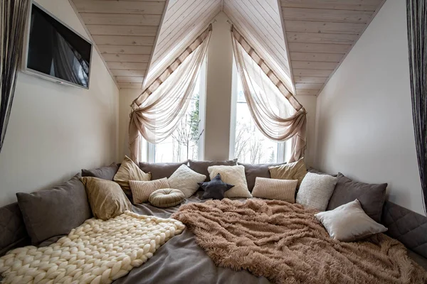 大きな柔らかい休憩所とモダンな家の広々とした廊下のインテリア 木製のロフト天井の上に多くの枕やライトウィンドウと現代的な広いソファ — ストック写真