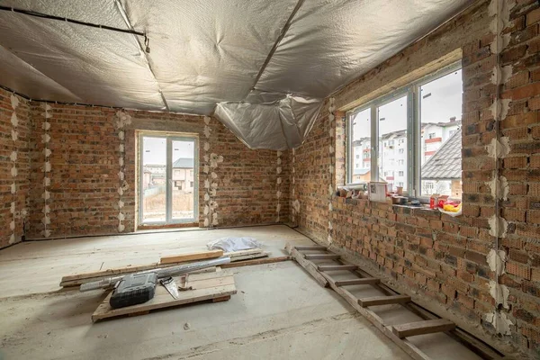 コンクリートの床と裸の壁と未完成のレンガ造りの家のインテリアは 建設中の漆喰の準備ができています 不動産開発 — ストック写真