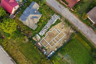 Geleceğin tuğla evi, beton temel zemini ve inşaat için sarı kil tuğla yığınları için hava manzarası.