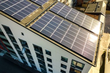 Temiz elektrik üretmek için konut bloğunun çatısındaki güneş fotovoltaik panellerin hava görüntüsü. Özerk konut kavramı.