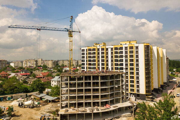 Workers working on concrete frame of tall apartment building under construction in a city.