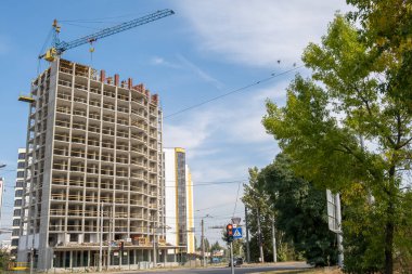 İnşaat halindeki yüksek apartmanın beton iskeleti ve bir şehirde kule vinci..