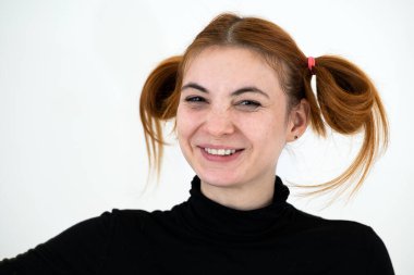 Kızıl saçlı komik bir kızın yakın plan portresi. Çocuksu saç stili, beyaz arka planda izole edilmiş mutlu bir şekilde gülümsüyor..